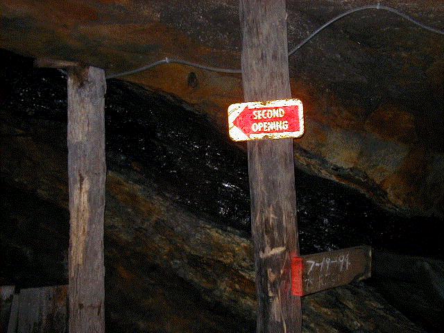 A sign shows the way out of the mine, via an emergency exit.